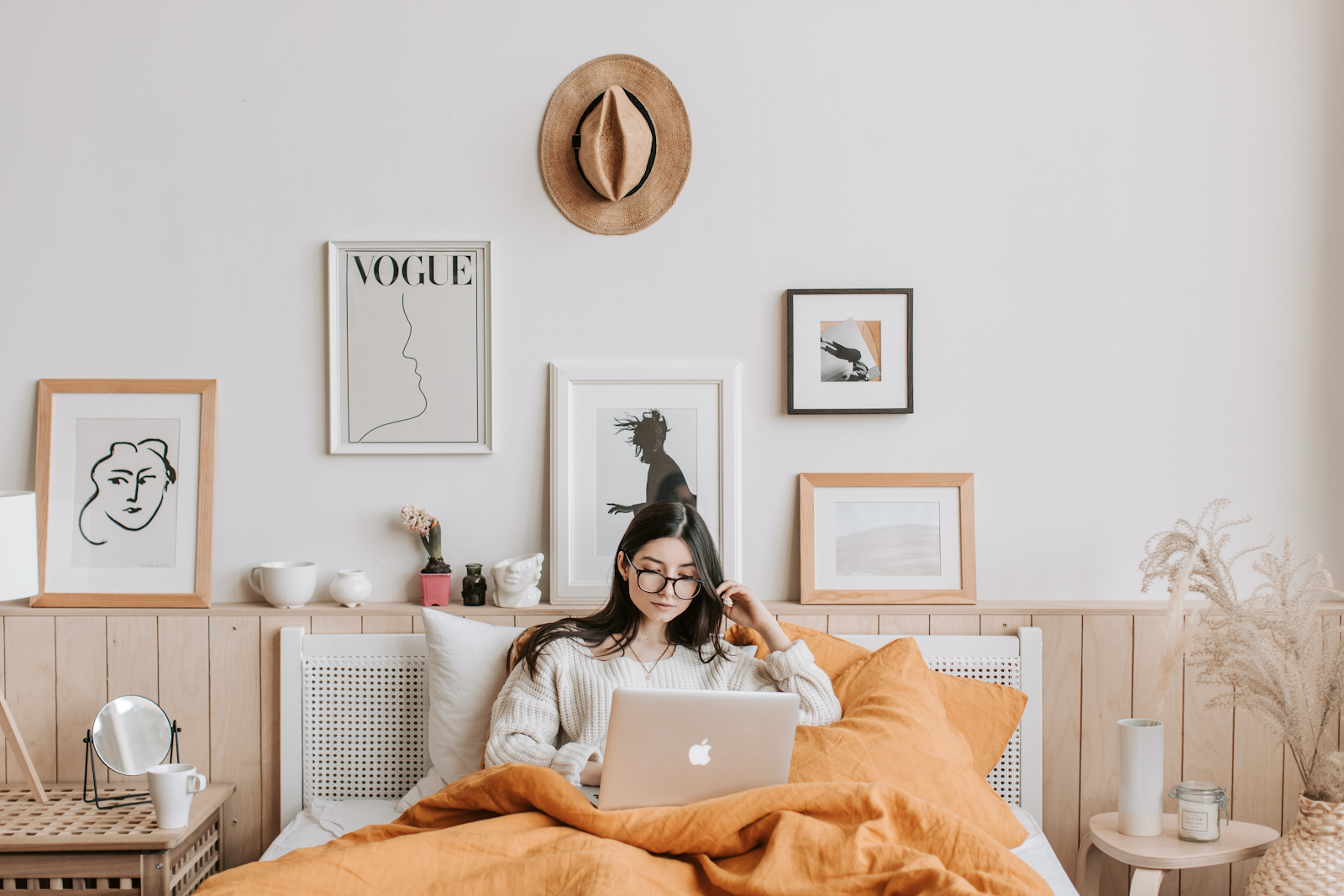 a woman on her laptop laying in bed staying comfortable with her properly maintained HVAC systems