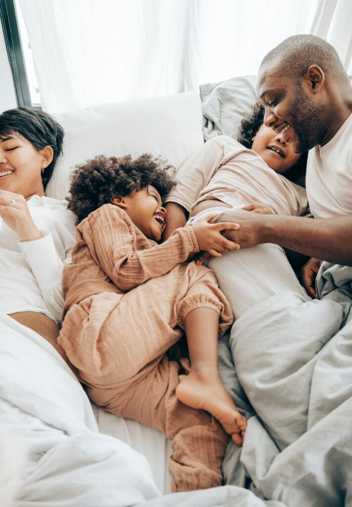 A happy and healthy family playing and spending time together in bed