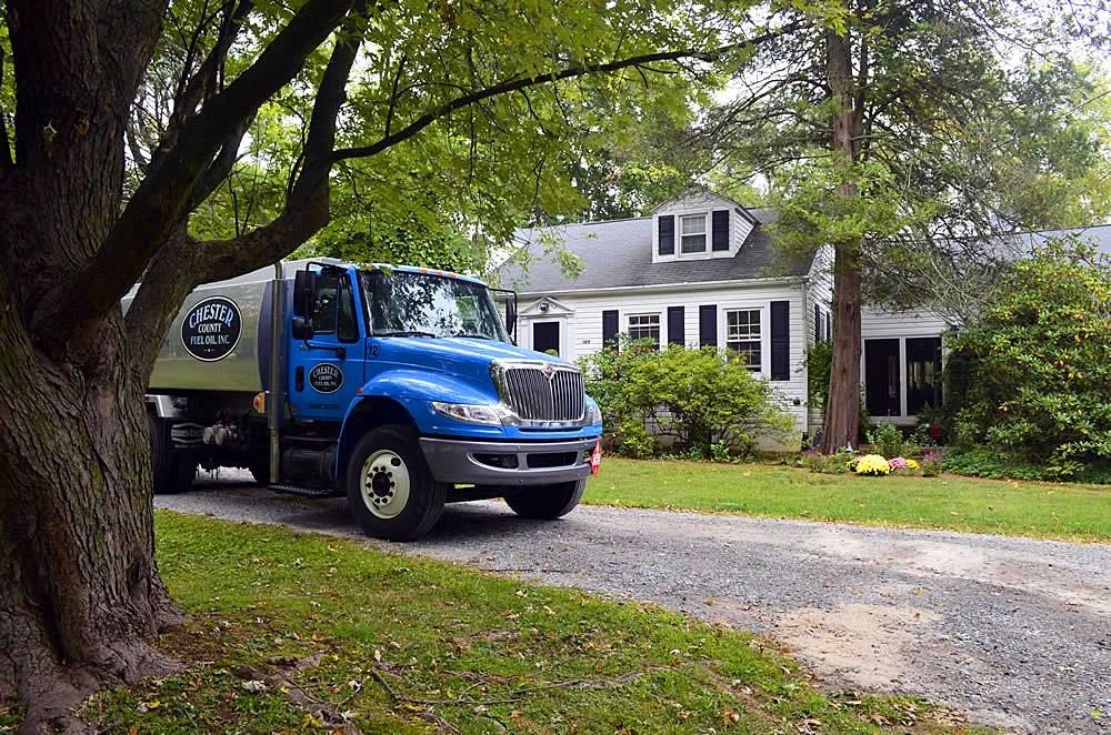 A Chester County Fuel Oil heating oil delivery truck parked in front of a Phoenixville, PA home