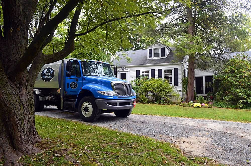 A Chester County Fuel Oil heating oil delivery truck parked in front of a Broomall, PA home